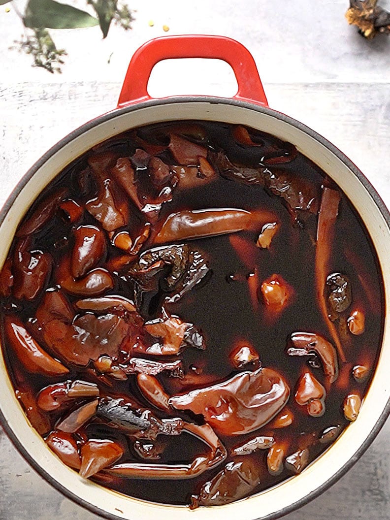 A red pot with cooked dried chiles in water.