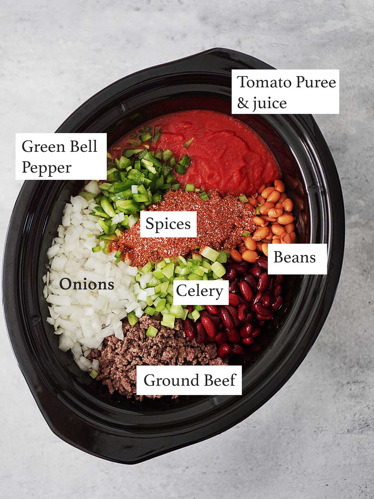 Beef chili ingredients in the dish of a crockpot.