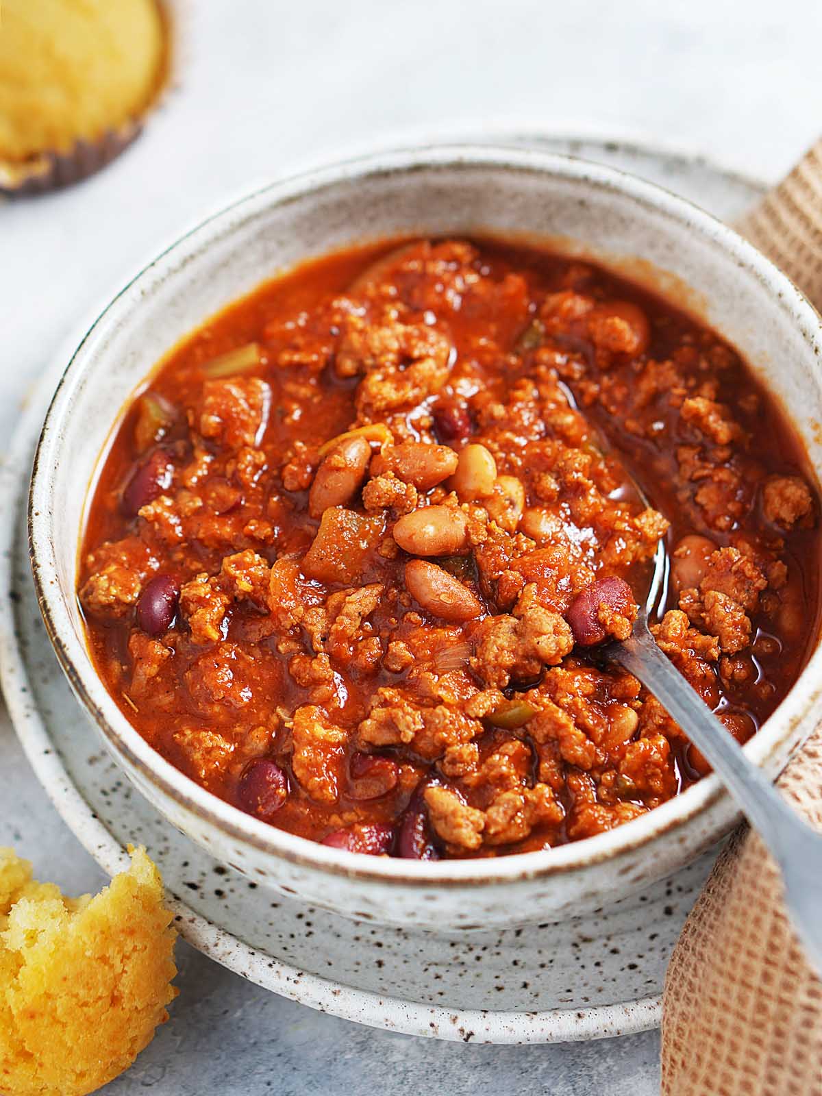 A bowl with chili with cornbread muffins on the side.