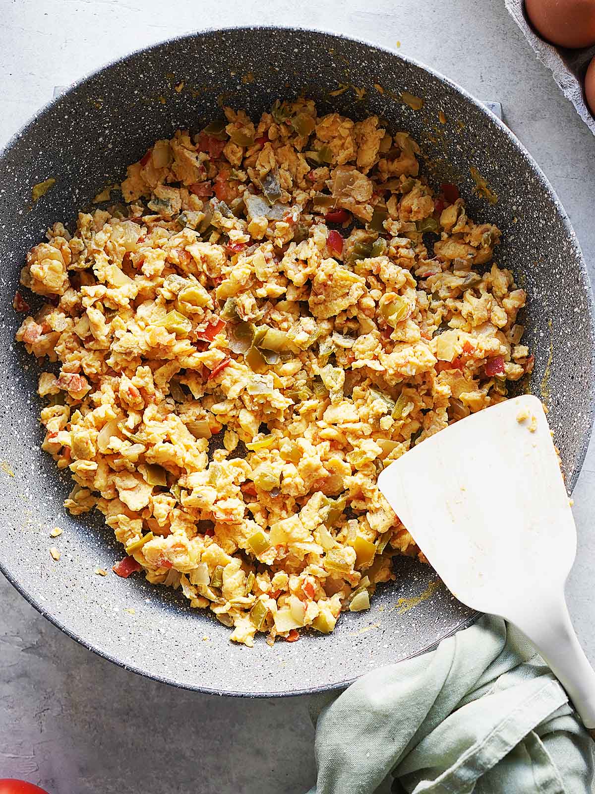 Scrambled eggs in a gray skillet.