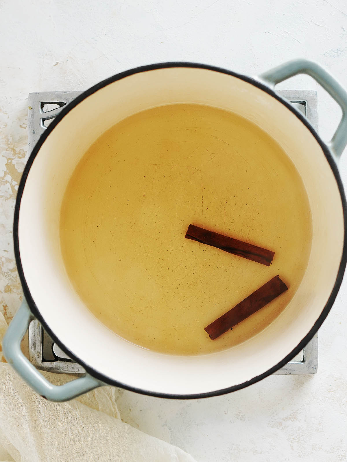 A medium pot with water and cinnamon sticks.