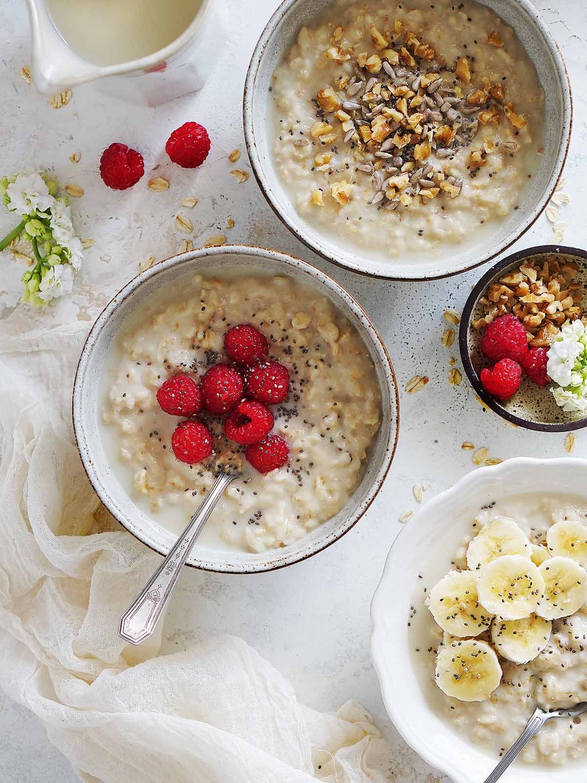 Three bowls of oatmeal topped with different fruits and nuts.