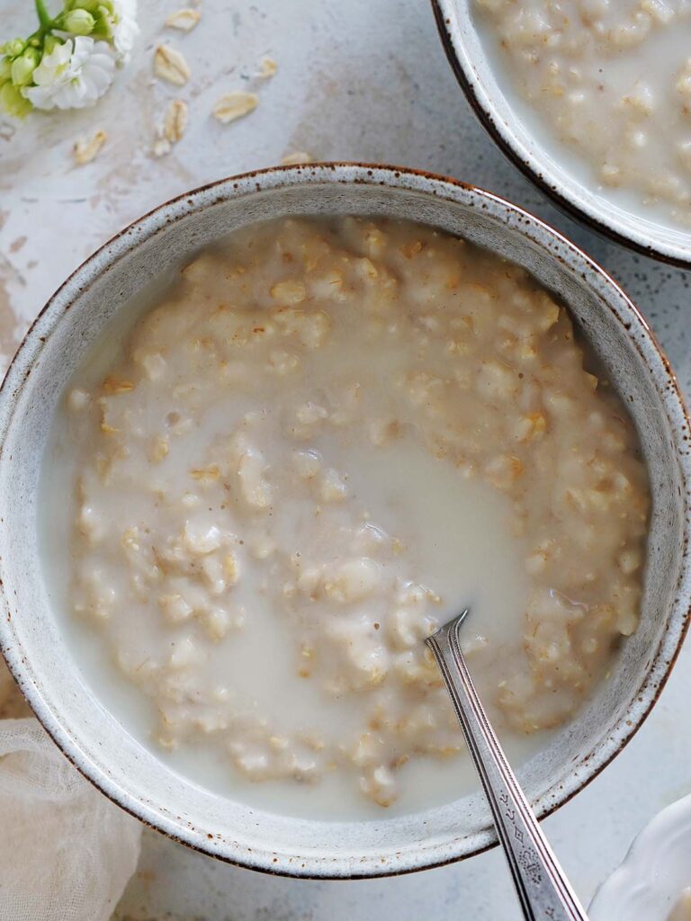 A bowl of oatmeal drizzled with some milk.