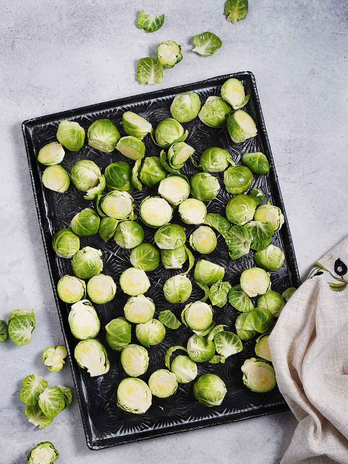A baking tray with brussel sprouts cut in half.