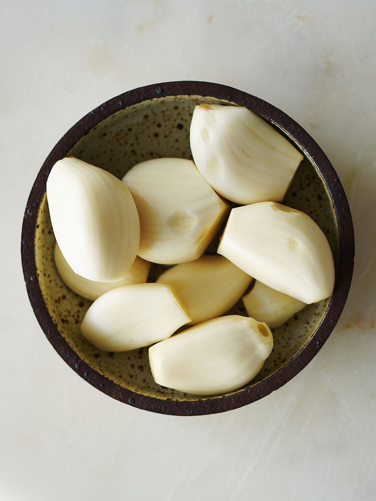 Fresh garlic cloves on a small little brown dish.