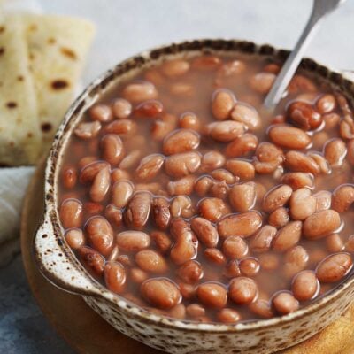 A bowl with cooked beans and a spoon.