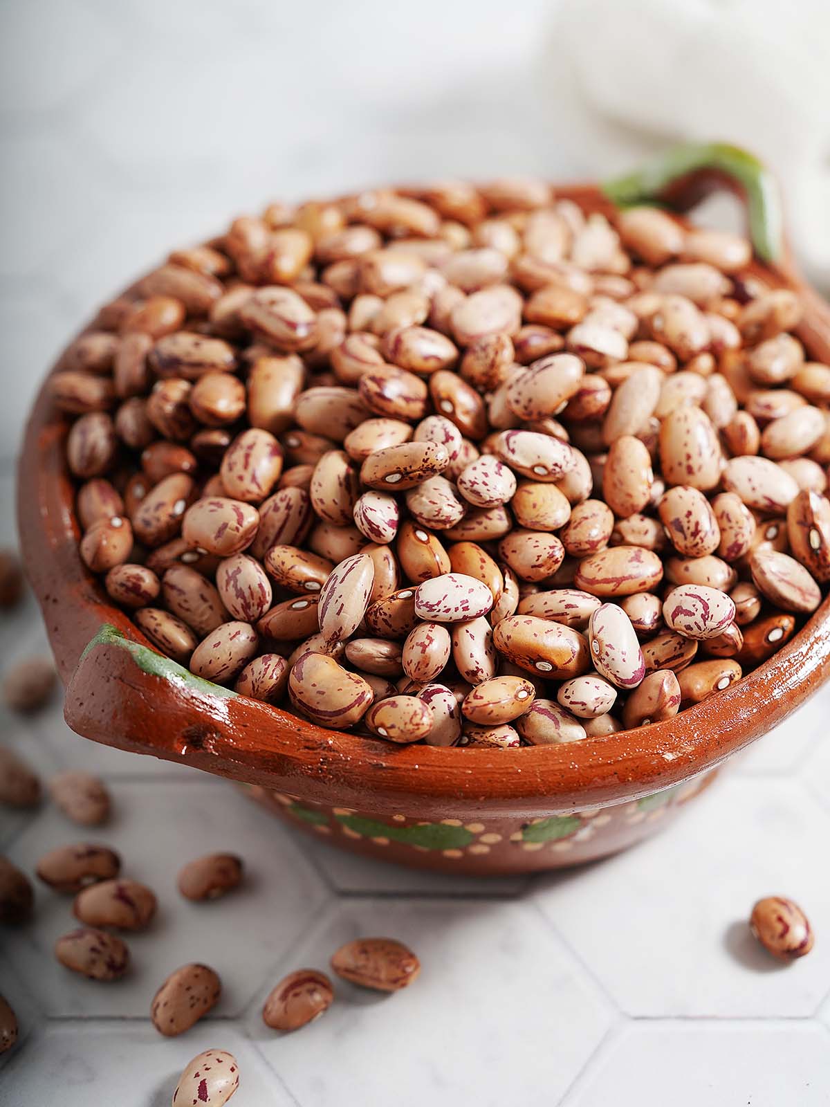 A barro bowl with raw pinto beans.