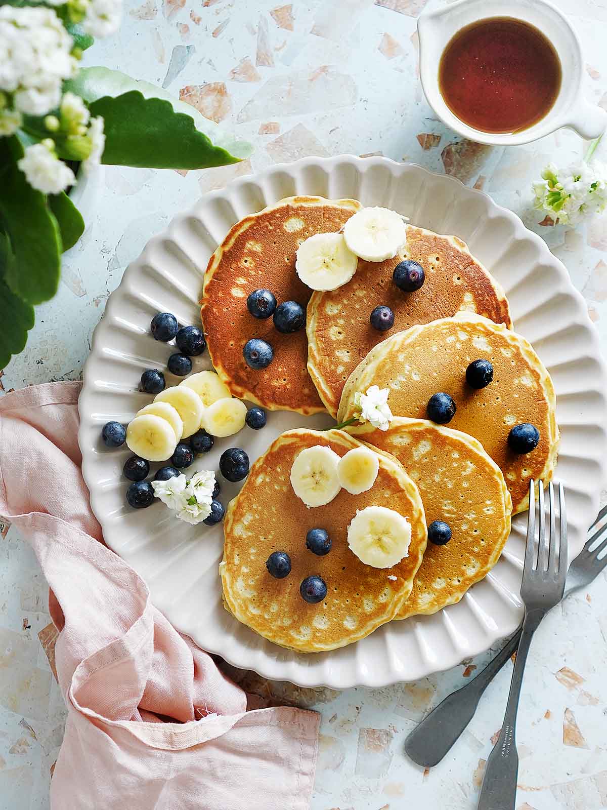Five pancakes on a plate with flowers on the side.