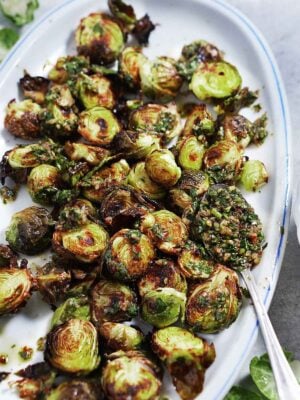 An oval plate with roasted brussel sprouts.