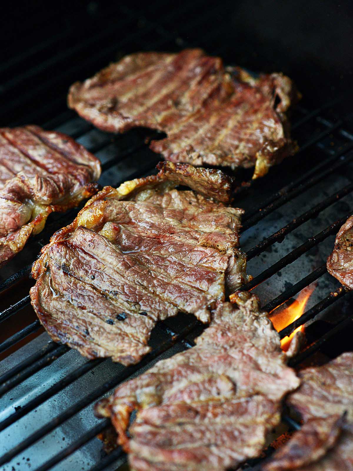 A grill filled with thin cooked carne asada.