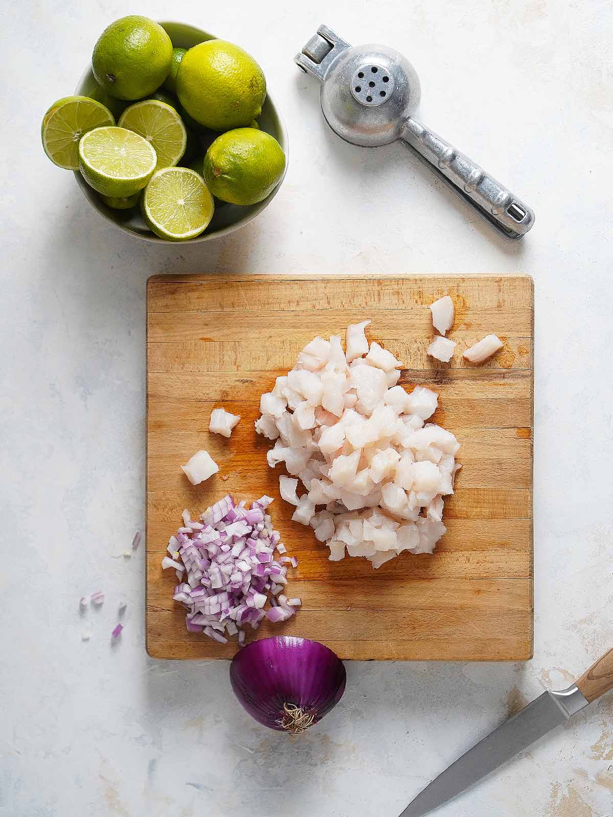 Chopped white fish on a wood cutting board.