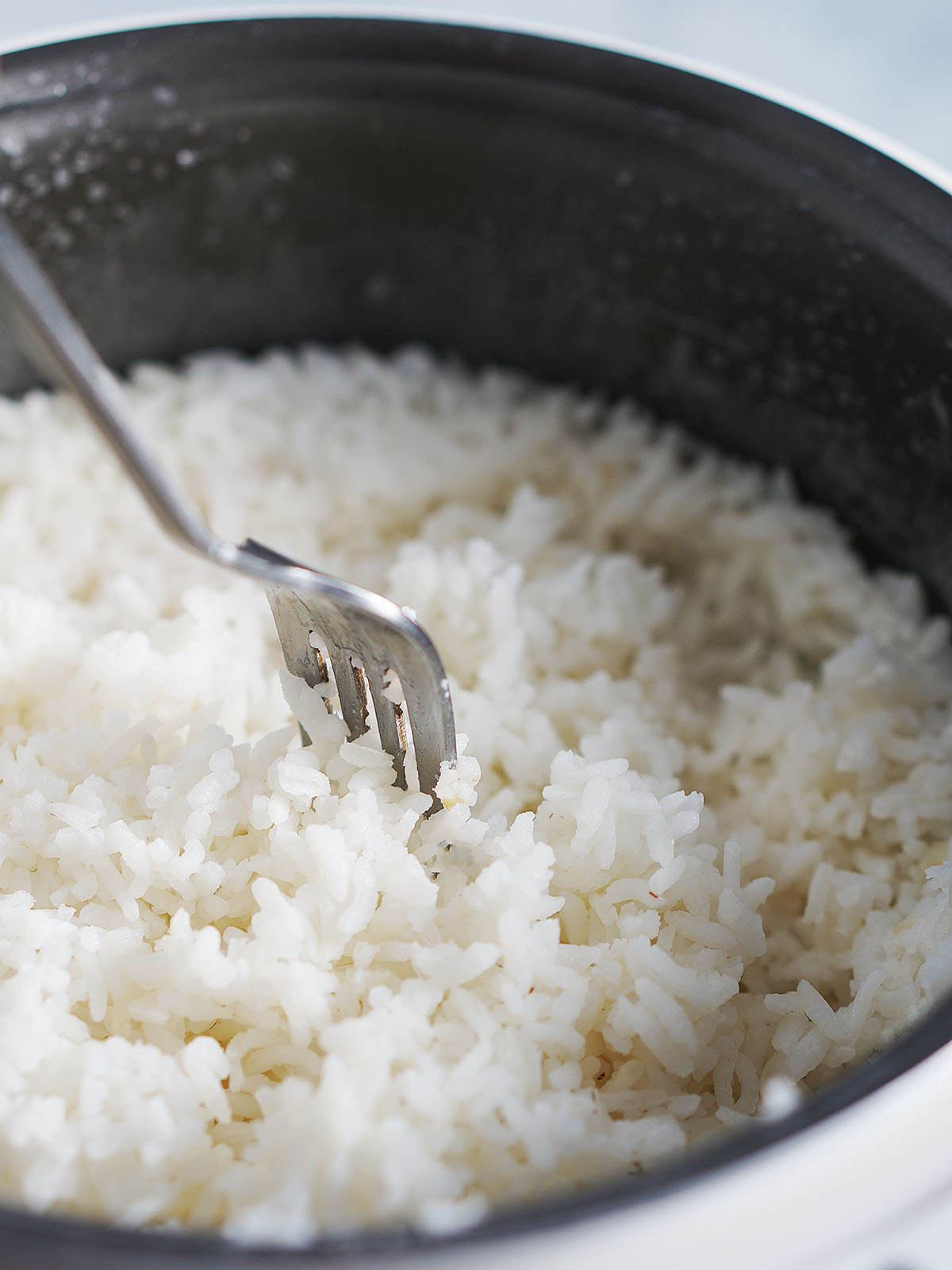 Fluffing cooked white rice with a fork.