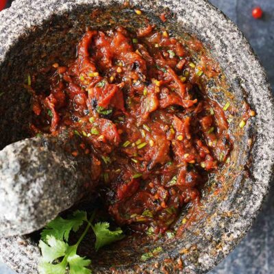 Chunky salsa with roasted vegetables in a molcajete.