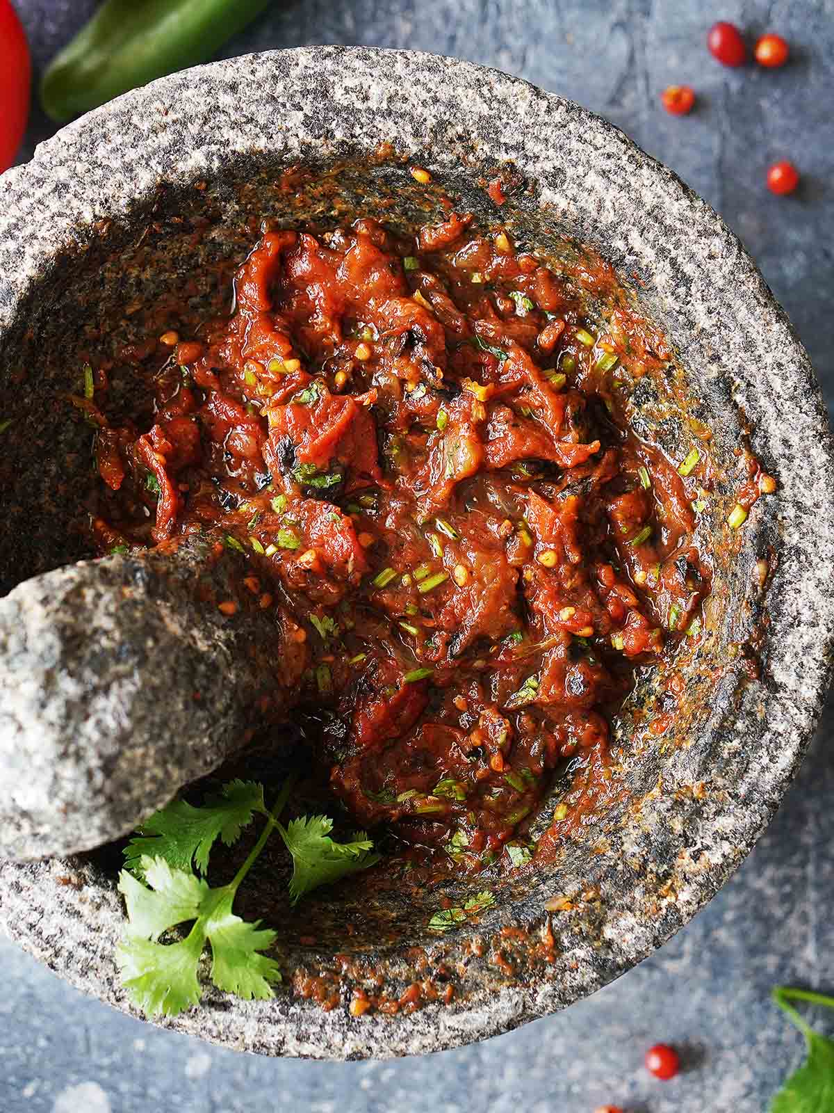 Chunky salsa with roasted vegetables in a molcajete.