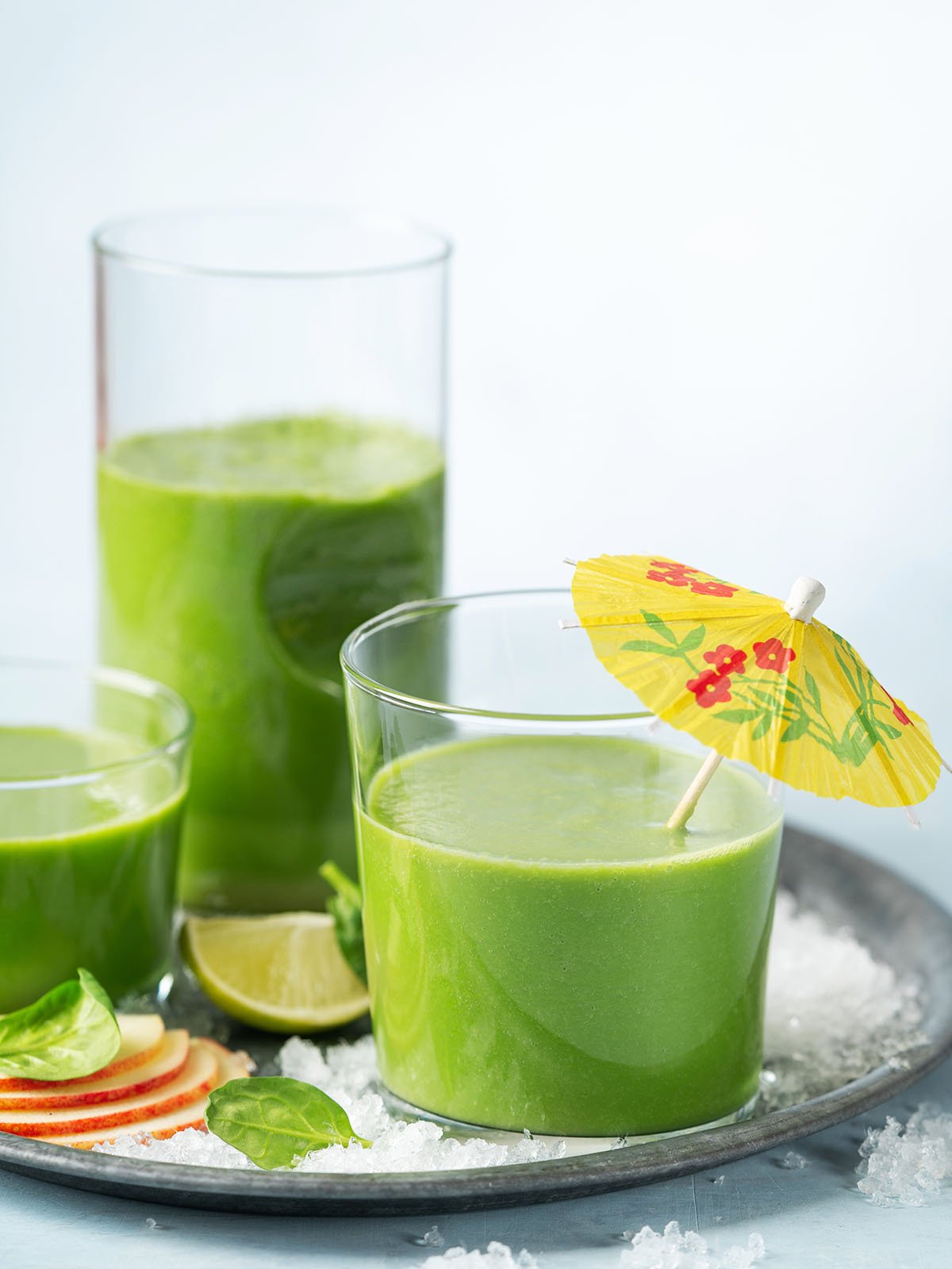 Green smoothie in glass with organic ingredients, vegetables on a light background.