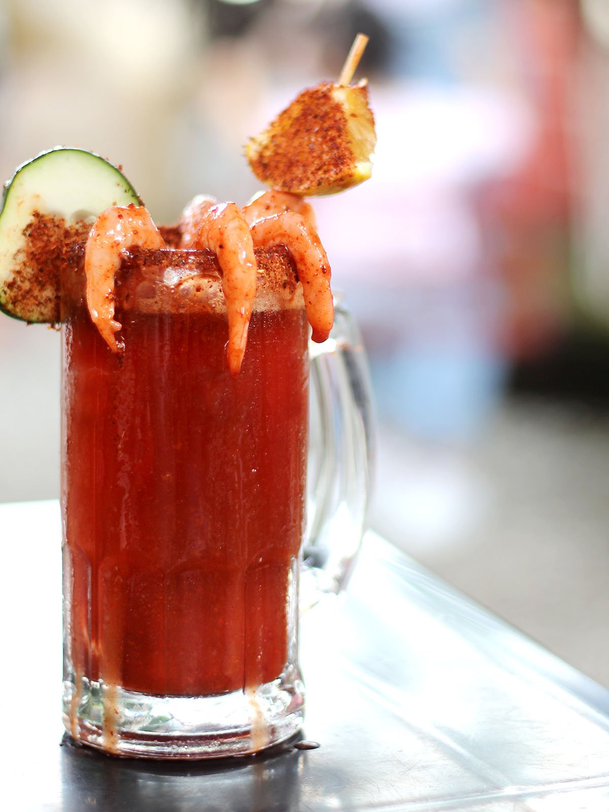 Micheladas served on an outdoor table, it is a Mexican alcoholic drink that is prepared by mixing beer, lemon juice, chili, salt and shrimp decorated with orange slices.