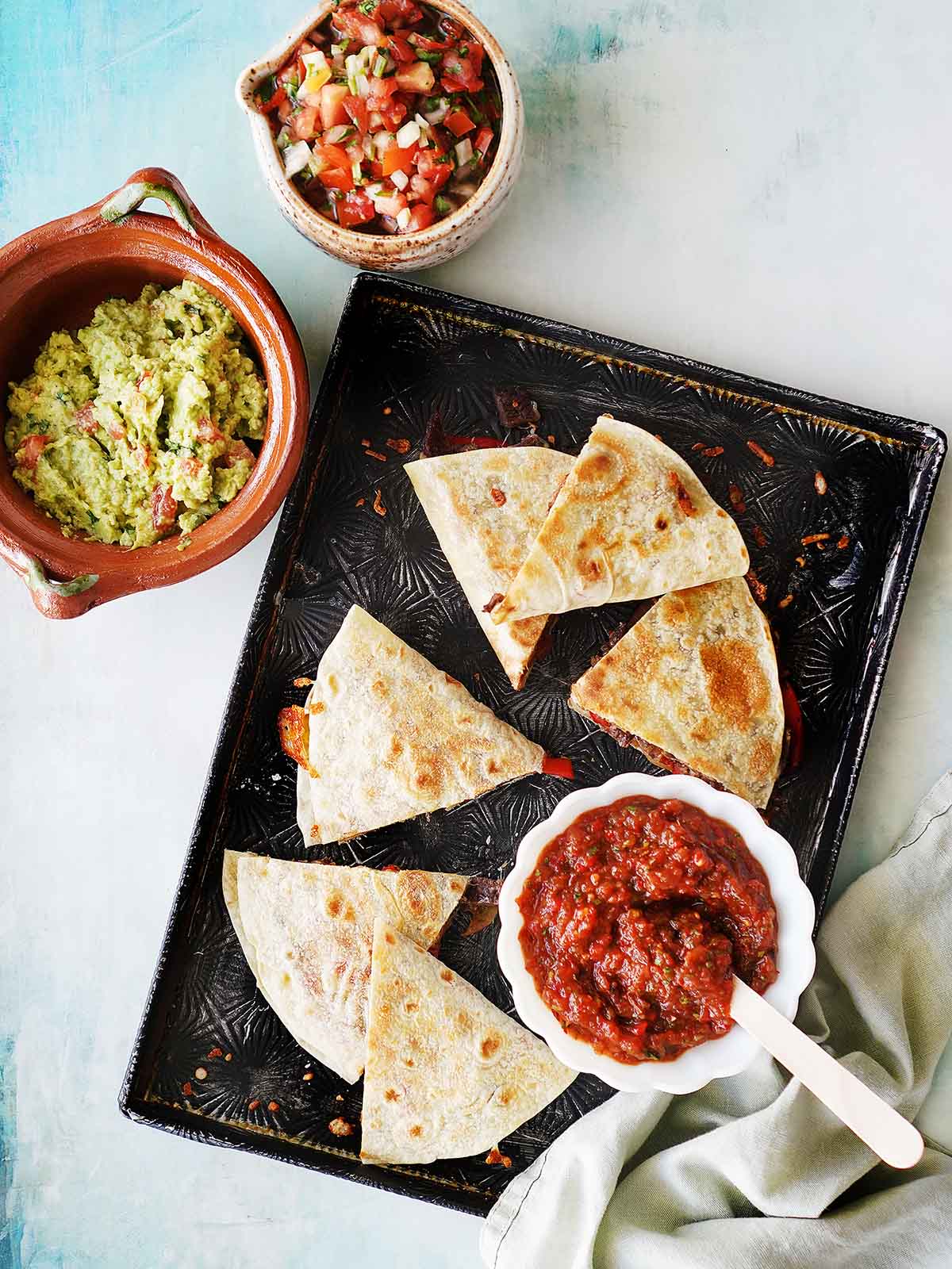 A baking tray with a quesadilla cut into triangle shapes.