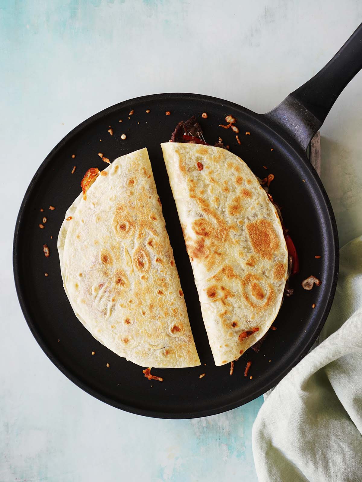Two crispy quesadillas on a skillet next to each other.