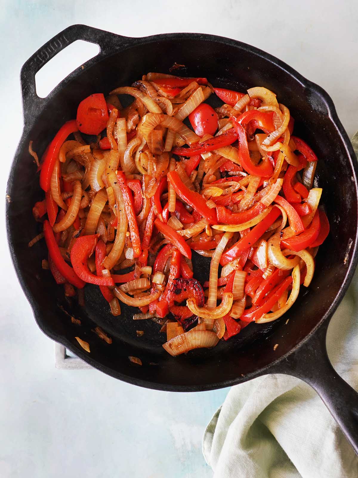 An iron skillet with sauteed onions and red bell peppers.