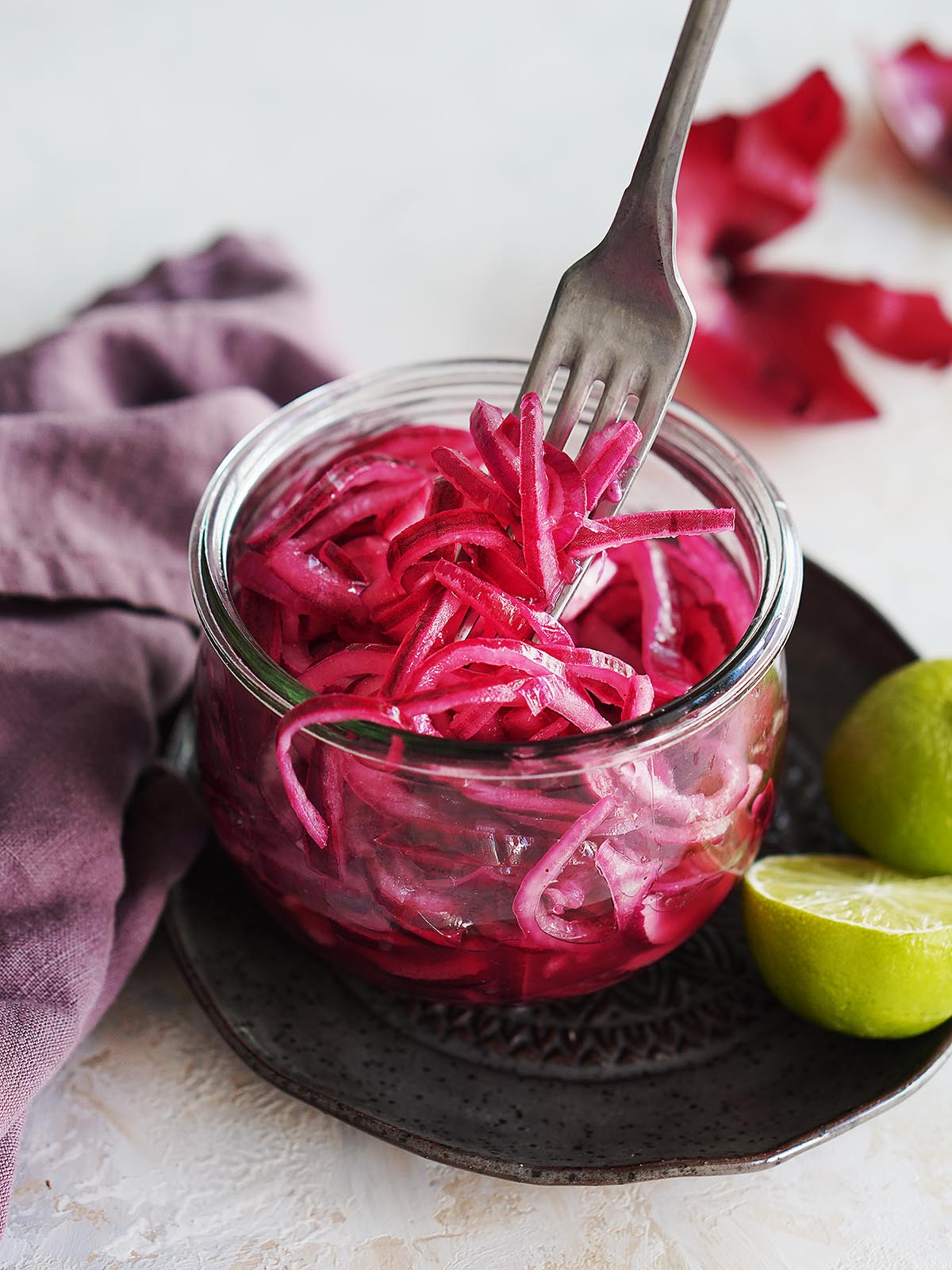 A small clear jar with Mexican Pickled Onions and a fork.