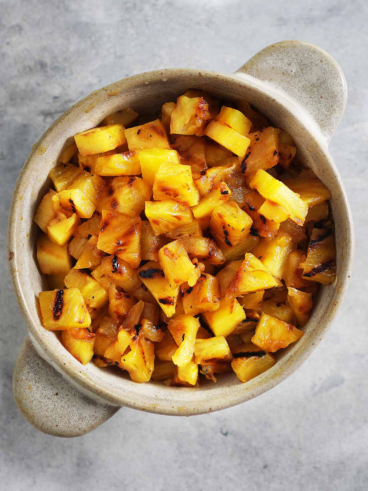 Small grilled pineapple chunks in a bowl.