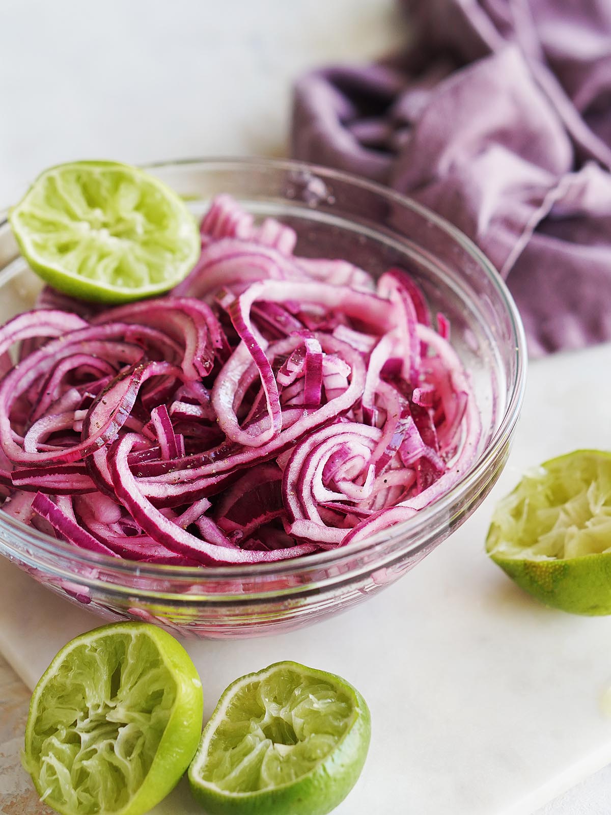 A bowl with sliced red onions and squeezed limes on the side.