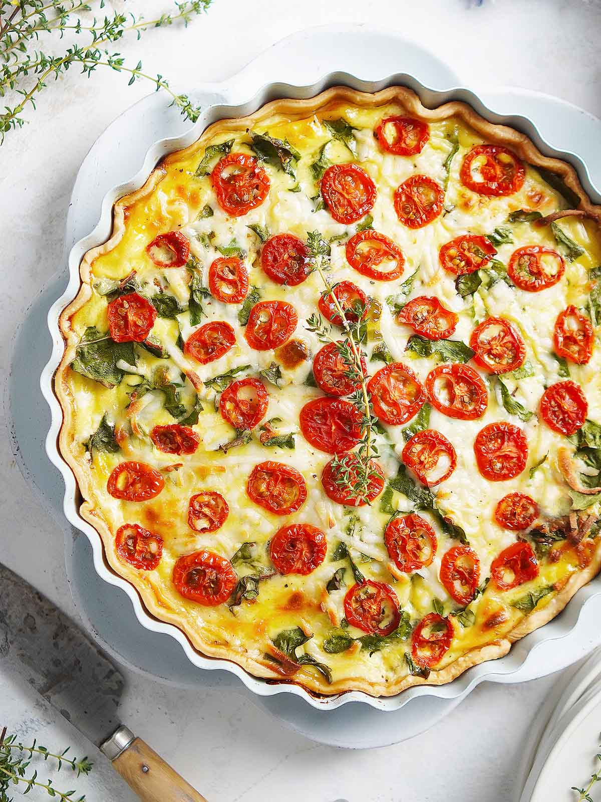A baked quiche with sliced tomatoes on top.