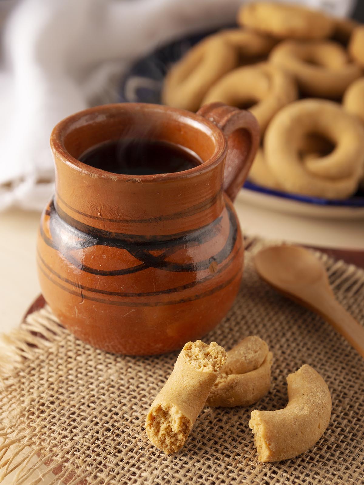 A clay mug with coricos cookies on the side.