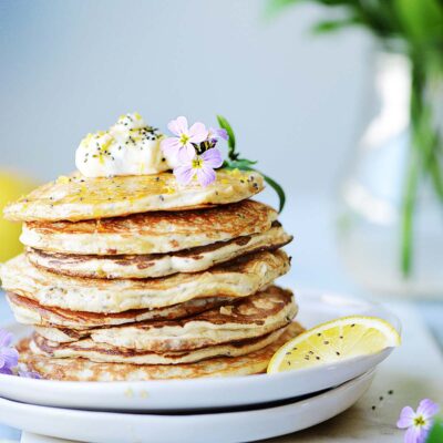 A stack of lemon protein pancakes with a plant in the background.