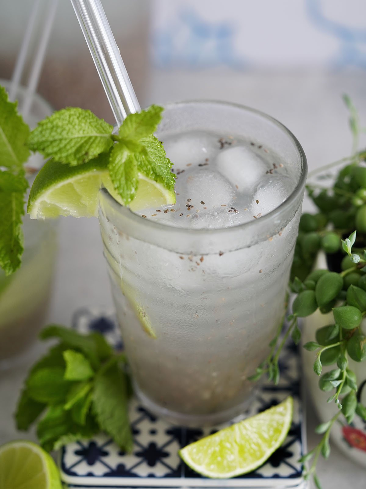 A glass with Agua Con Chia & Limon garnished a slice of lime and mint.