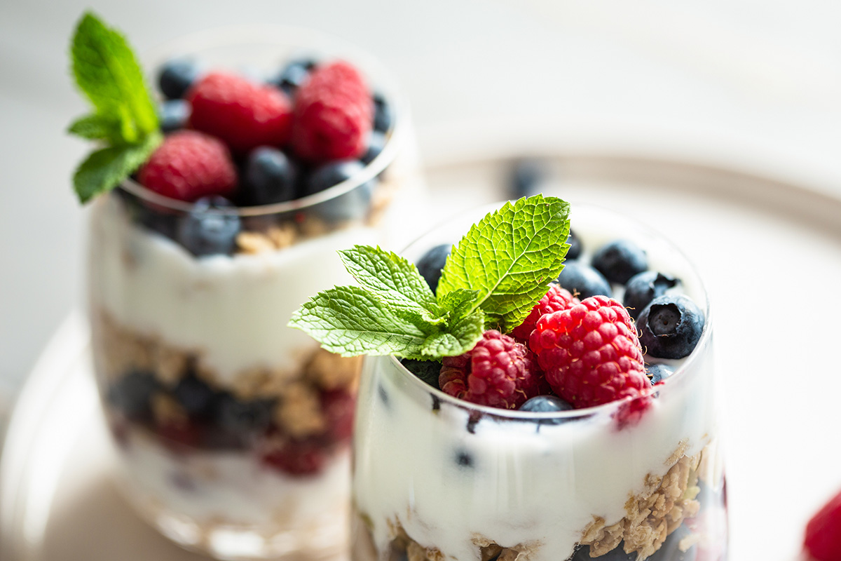 Two glasses of parfait made of granola, berries and yogurt on the table. Close up view, selective focus.