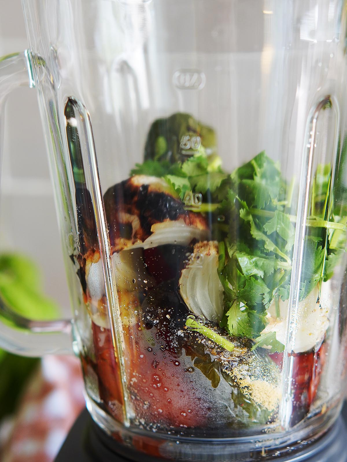 All of the ingredients including fresh cilantro inside a blender's cup.