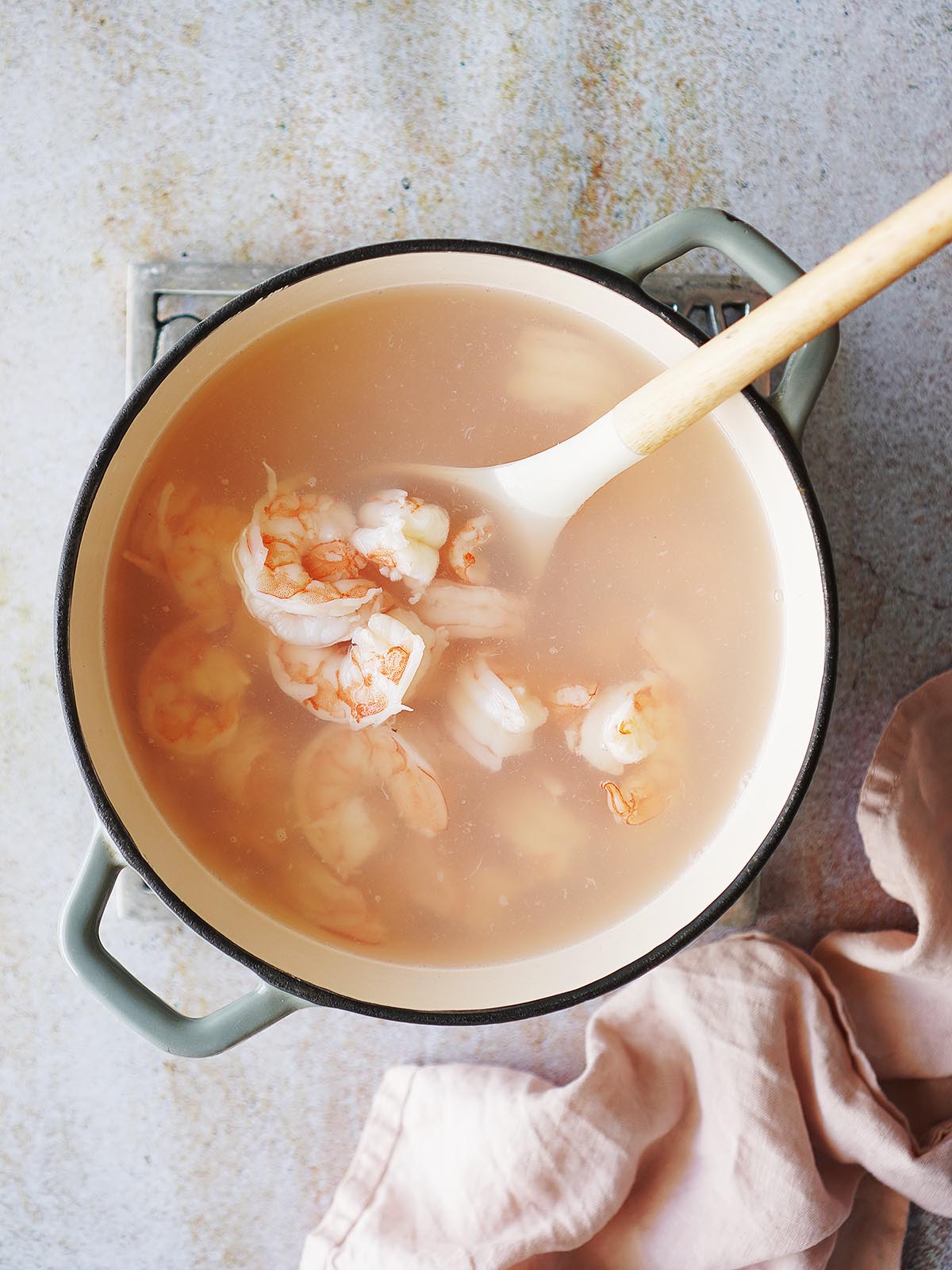 Boil shrimp in a small saucepan with a cooking spoon inside.