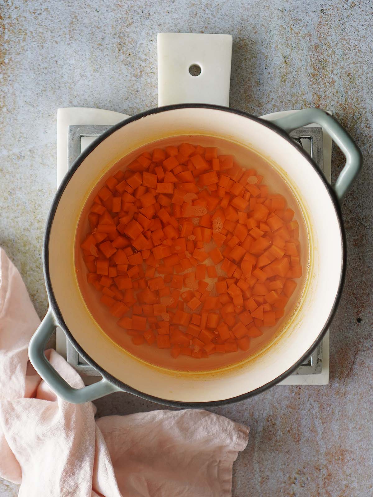 Cooked chopped carrots inside a small saucepan.