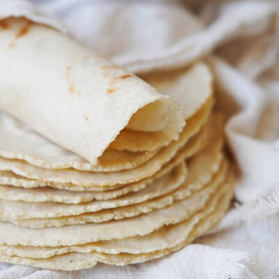 A stack of tortillas with one rolled on top.