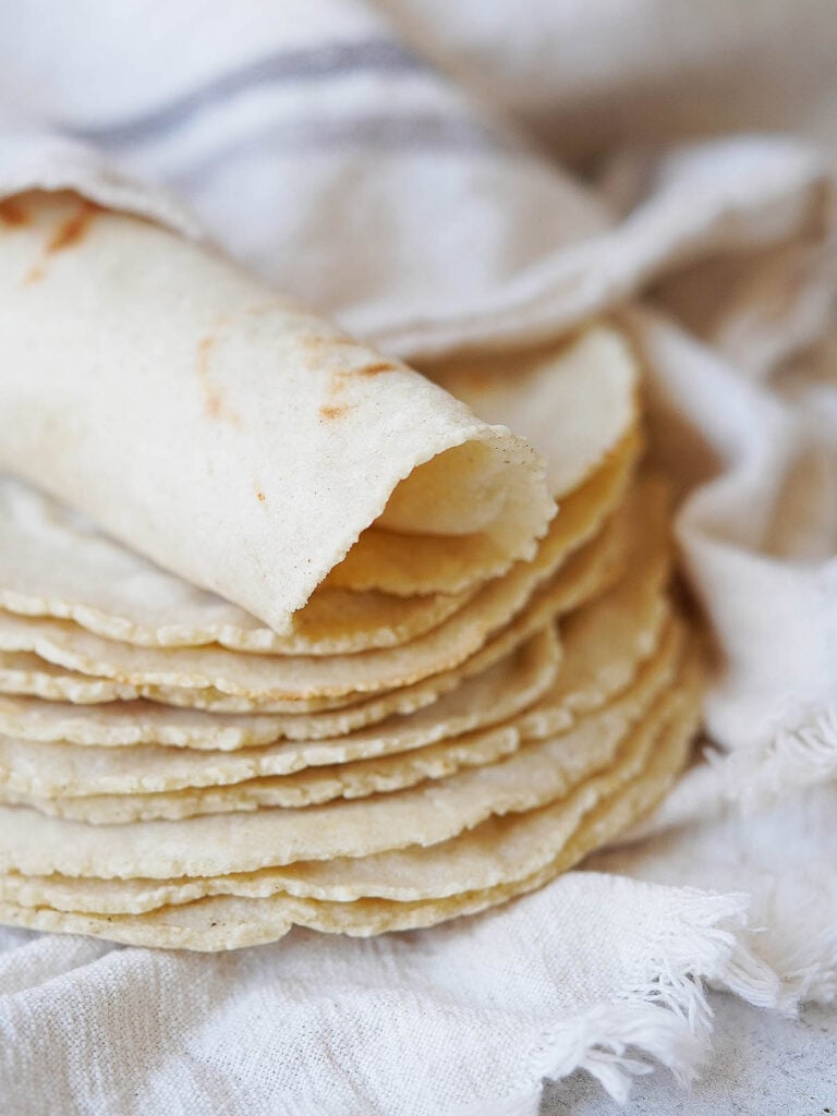 A stack of tortillas with one rolled on top.