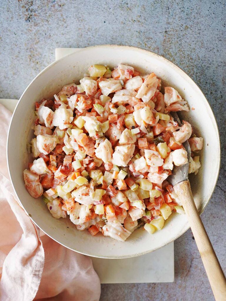 Creamy Shrimp Salad in a pink kitchen towel next to the bowl.