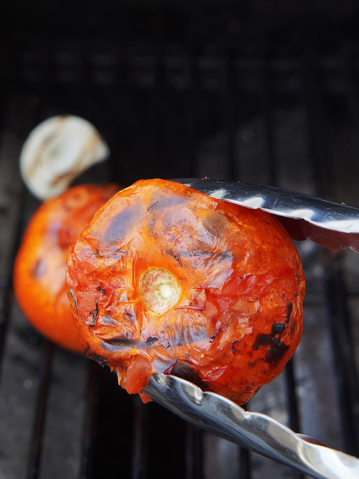 A roasted tomato grabbed by tong.