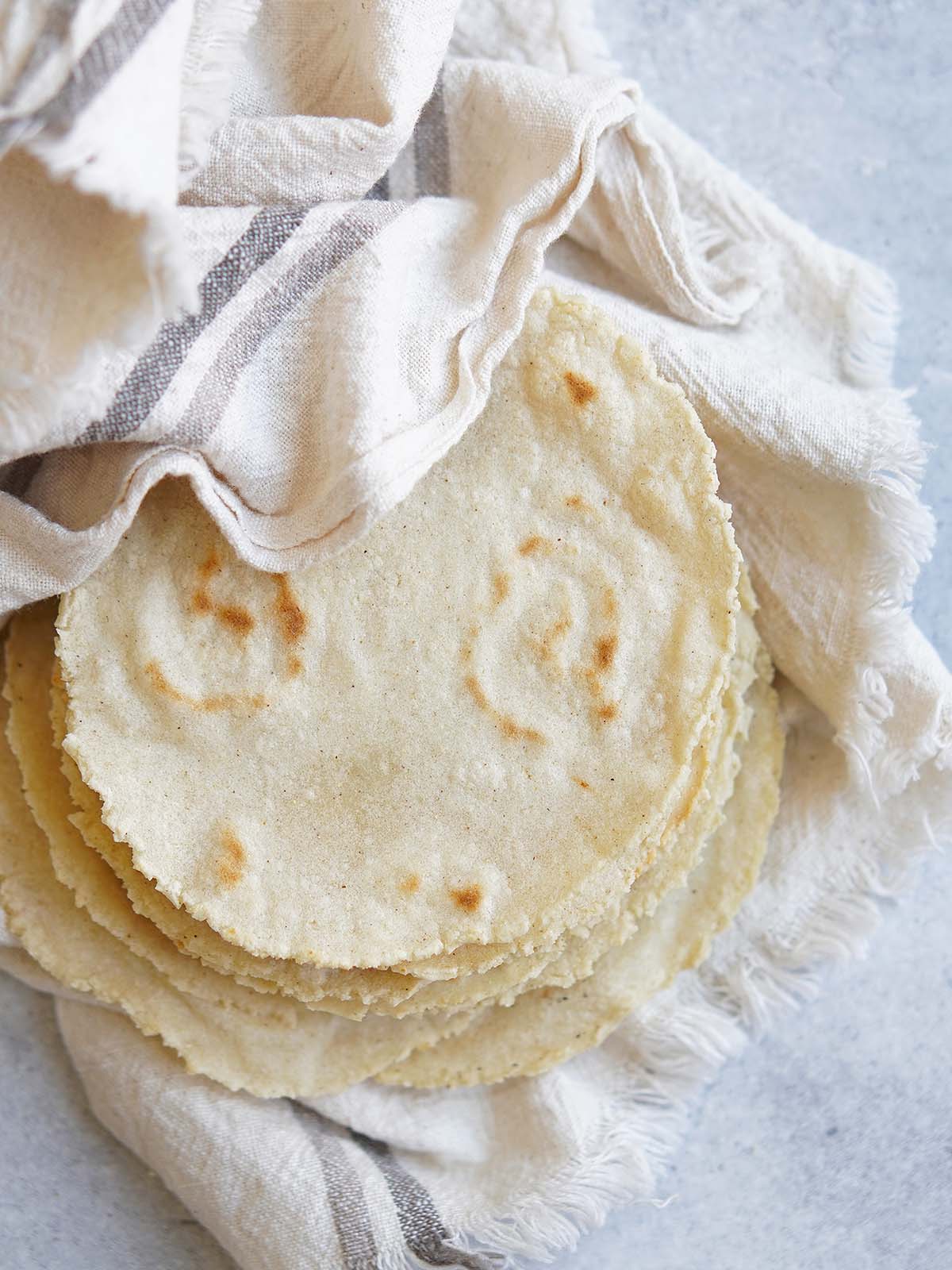 Some cooked corn tortillas inside a kitchen towel.