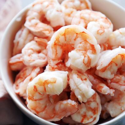 A white bowl with cooked shrimp.