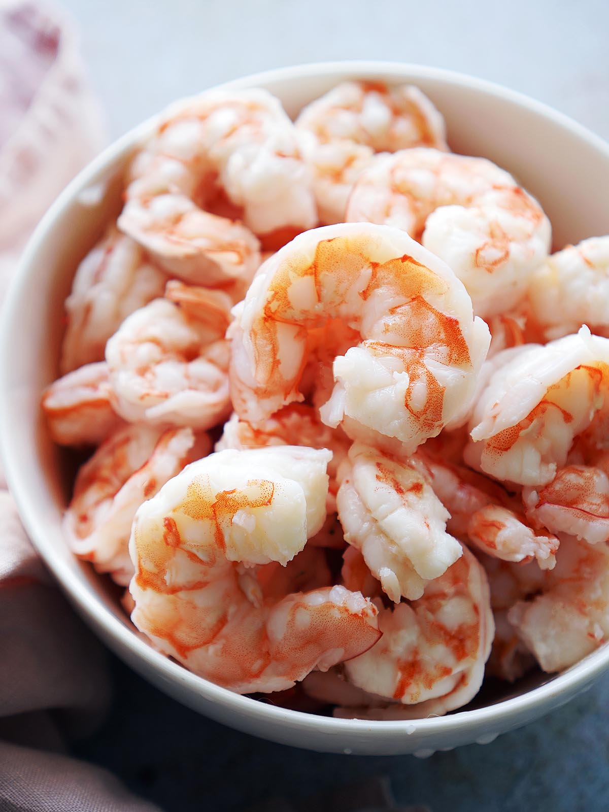 A white bowl with cooked shrimp.