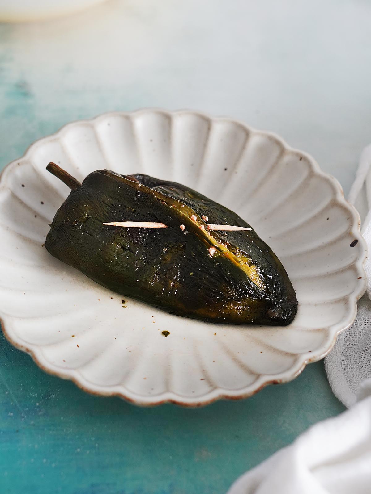 A roasted poblano pepper stuffed with a toothpick across the slit.