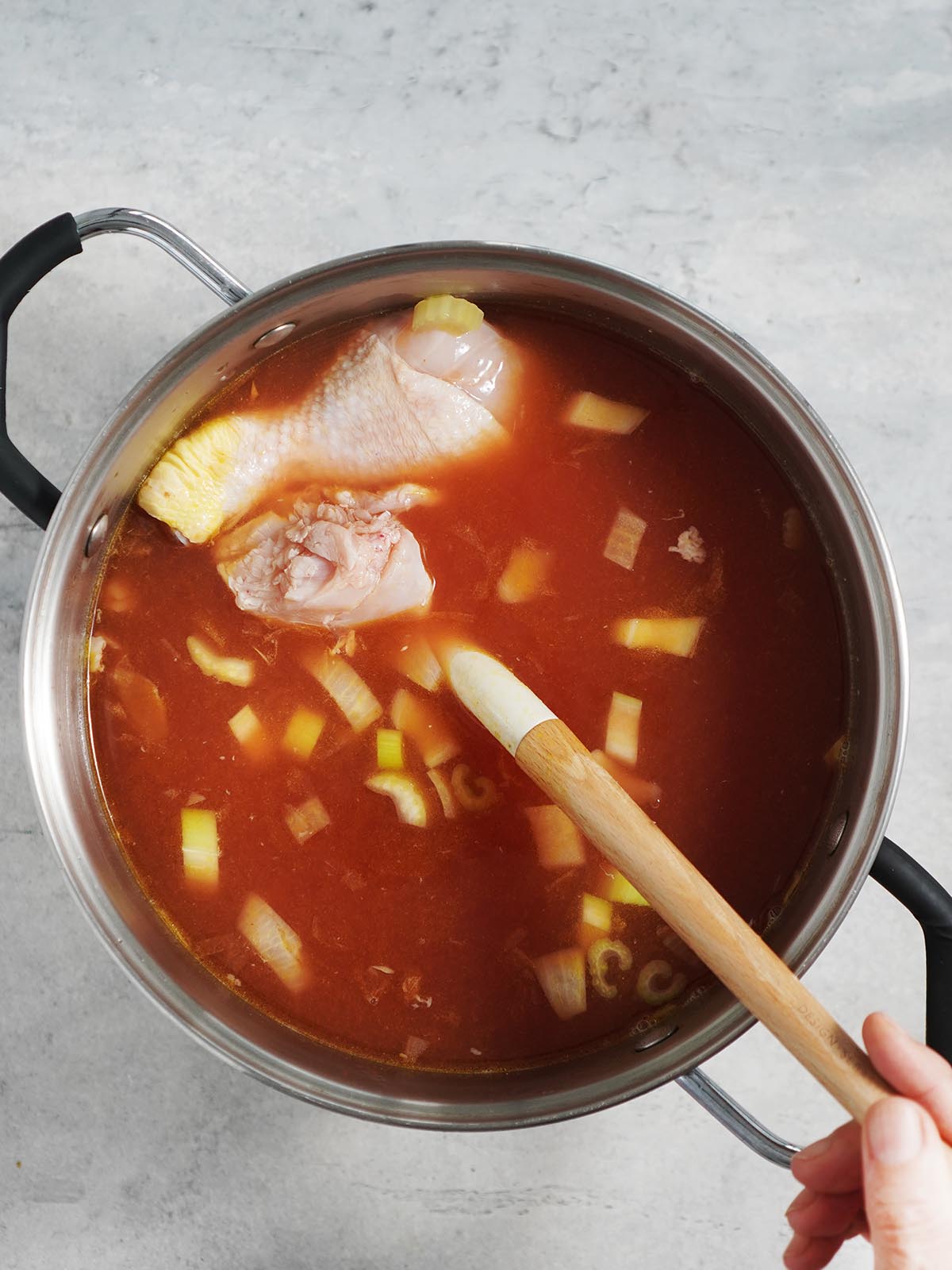 A large stock pot with the raw chicken in the broth.