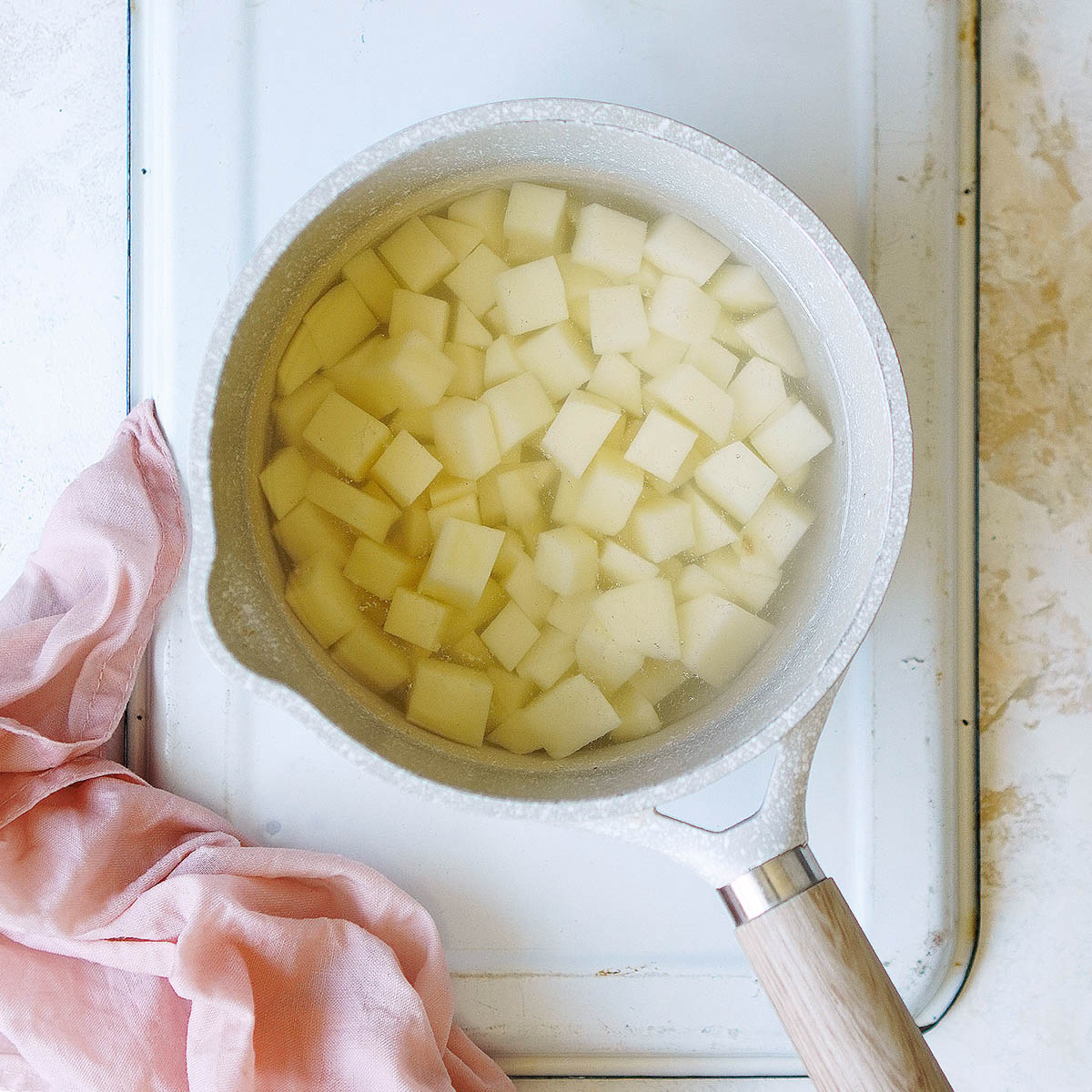 Cubed potatoes in a small saucepan with water. and then being drained on paper towels.