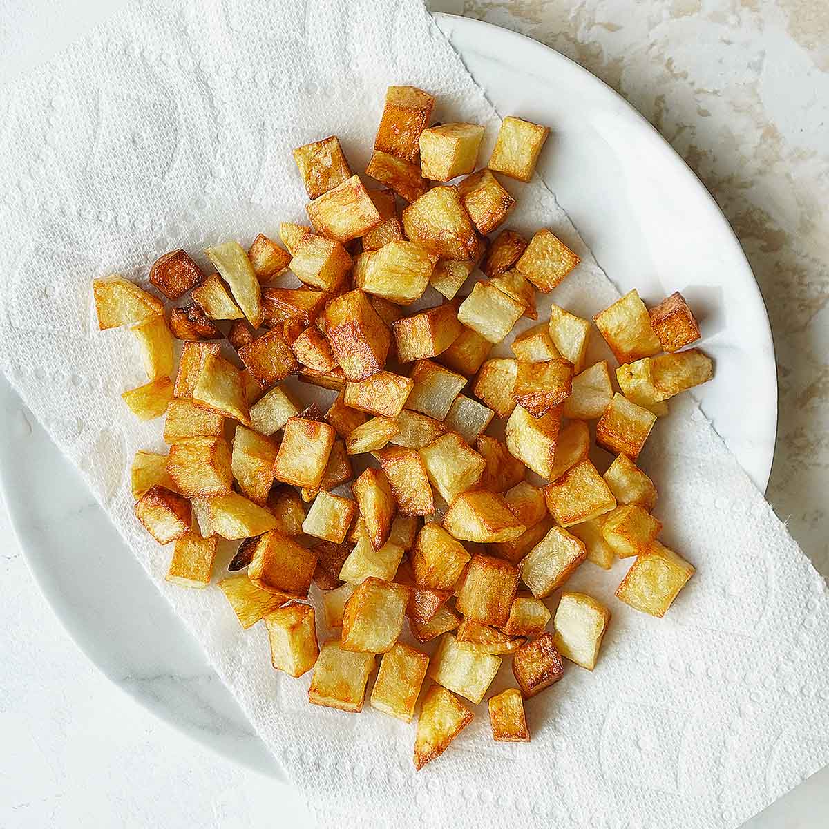 Fried cubed potatoes on a paper towel.