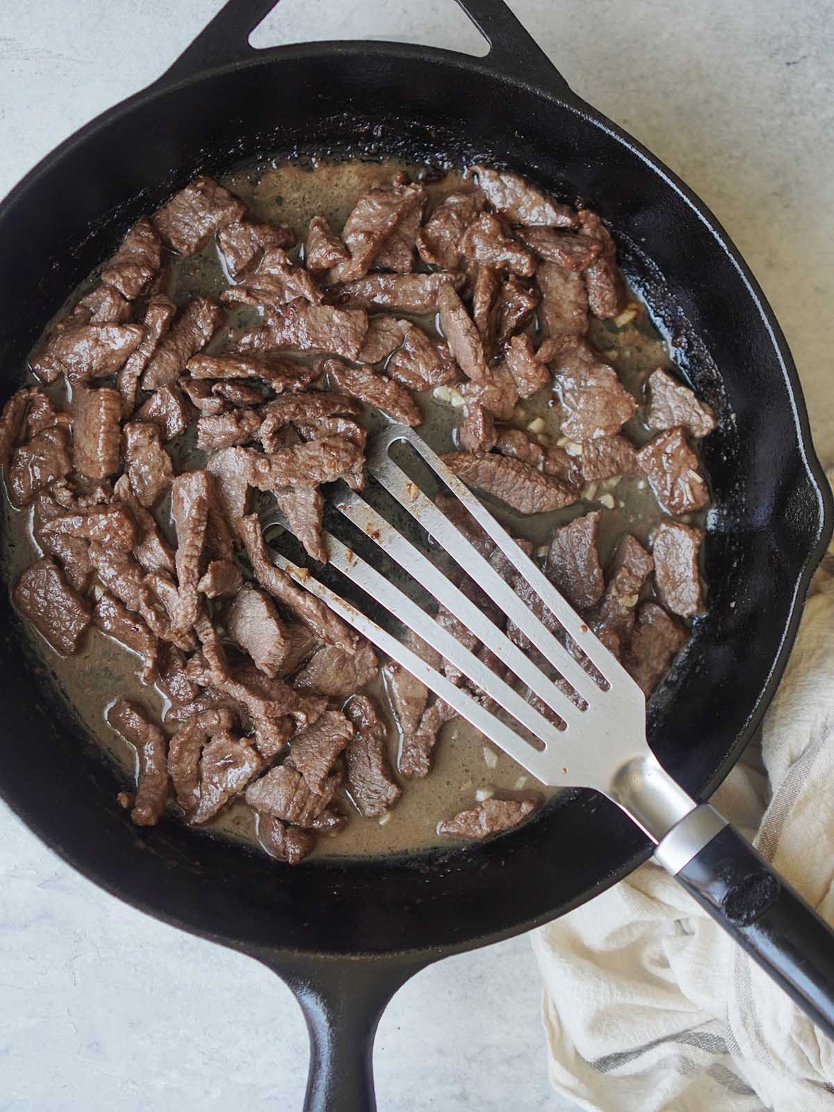 A skillet with cooked beef.