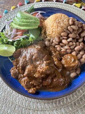 A plate with chicken, beans and mexican rice.