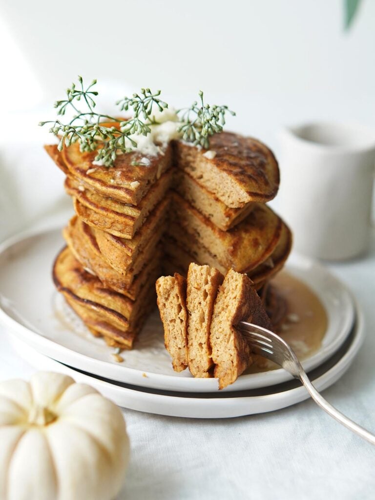 A stack of pumpkin pancakes with slices cut out.