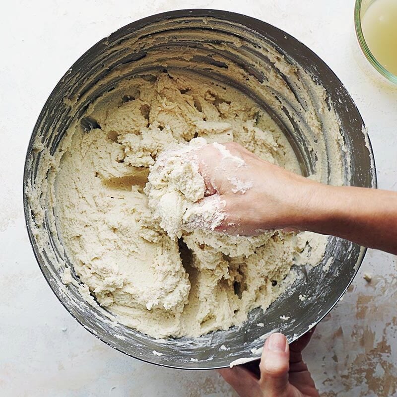 Mixing dough with one hand in a large bowl.