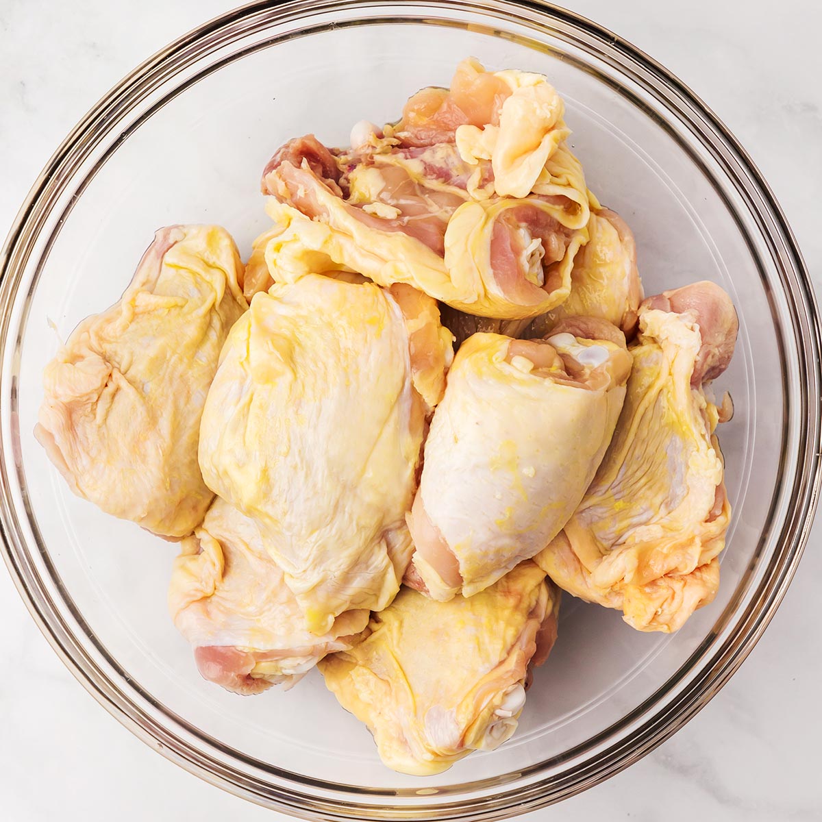 Raw chicken pieces in a mixing bowl.